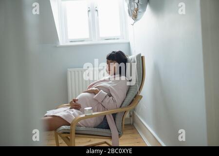 Tired pregnant woman napping in bathrobe Stock Photo