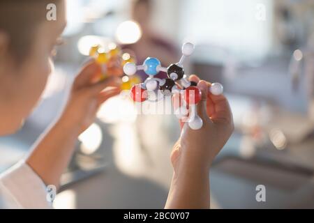 Curious girl student holding molecule model in classroom Stock Photo