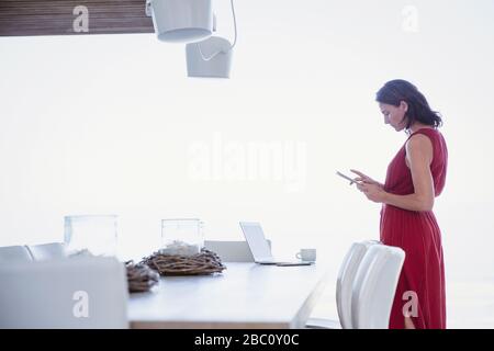 Woman using digital tablet, working at dining room table Stock Photo