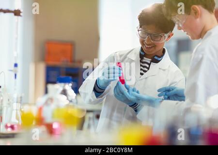 Boy students conducting scientific experiment, examining liquid in test tube in laboratory classroom Stock Photo