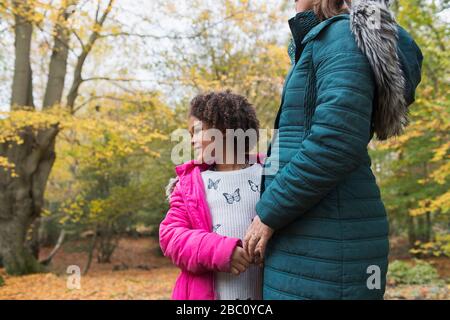 Happy daughter holding hands with mother in autumn woods Stock Photo