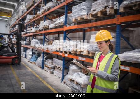 Female worker with clipboard checking inventory in warehouse Stock Photo