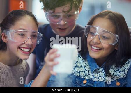 Curious, smiling students watching chemical reaction, conducting scientific experiment in laboratory classroom Stock Photo