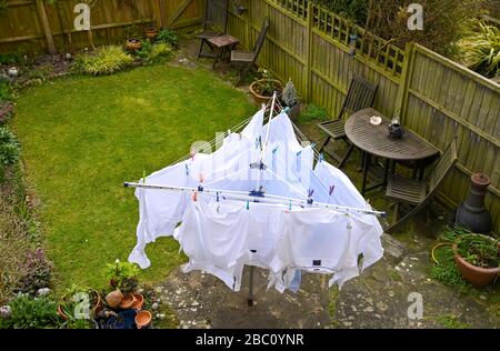 White mens shirts hanging on a rotating washing line during in the wind in back garden UK Stock Photo