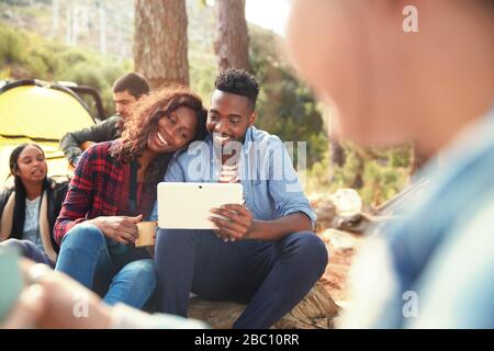 Smiling young couple using digital tablet at campsite Stock Photo