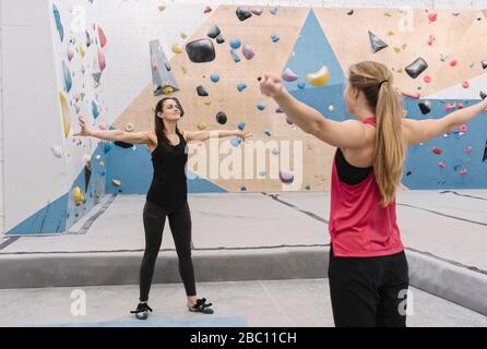 Two women doing stretching exercises before climbing on the wall Stock Photo