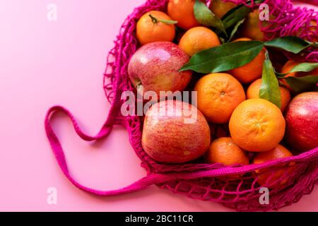 Fresh clementines and apples in eco-friendly reusable mesh bag Stock Photo