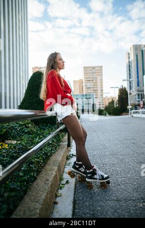 Young woman on roller skates leaning against railing in the city Stock Photo