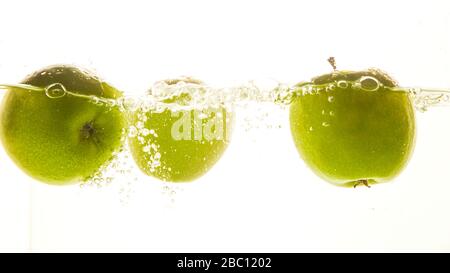Green apples in the water with water splash on white background. Stock Photo