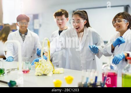 Surprised students conducting exploding foam scientific experiment in classroom laboratory Stock Photo