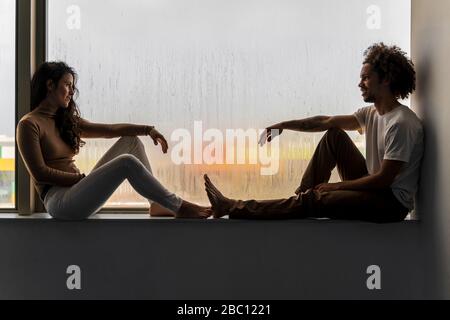 Flirting couple sitting in front of window Stock Photo