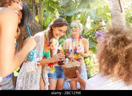 Young women friends laughing and drinking at summer party Stock Photo