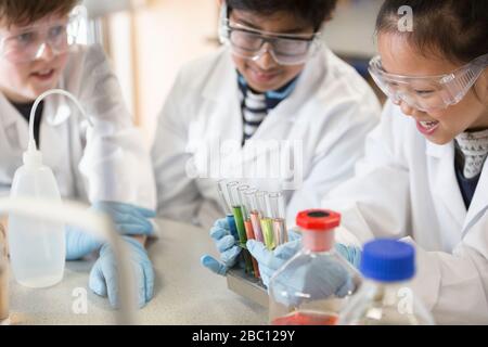 Students examining liquids in test tube rack, conducting scientific experiment in laboratory classroom Stock Photo