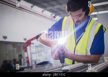 Male engineer with power drill assembling equipment in steel factory Stock Photo