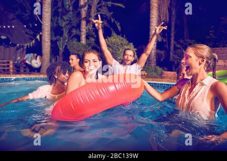 Portrait young friends playing in swimming pool at night Stock Photo
