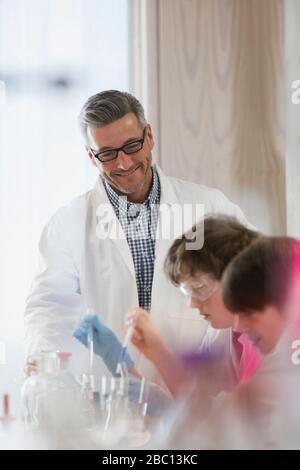 Male teacher and boy student conducting scientific experiment in laboratory classroom Stock Photo