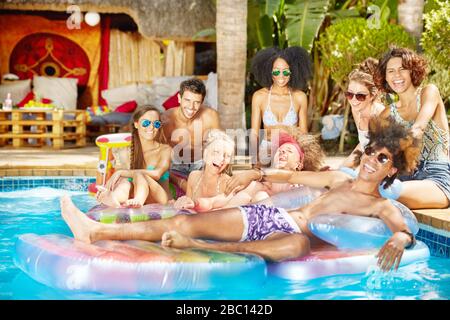 Portrait enthusiastic young friends hanging out in summer swimming pool Stock Photo