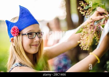Girl wearing a party hat picking elderberries in garden Stock Photo