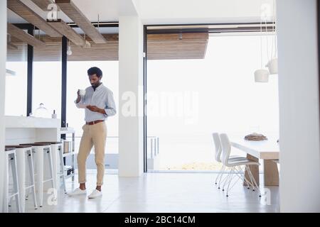 Businessman drinking coffee and using digital tablet in kitchen Stock Photo