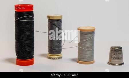 Composition of three spools of sewing thread tied together like a hug and a dressmaker's thimble Stock Photo