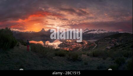 Hiker looking to Riano Lake and mountains at sunset,  Leon, Spain Stock Photo