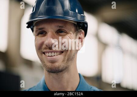 Portrait of a smiling worker in a factory wearing hard hat Stock Photo