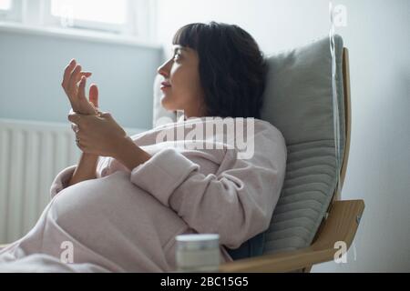 Pregnant woman in bathrobe rubbing hands Stock Photo