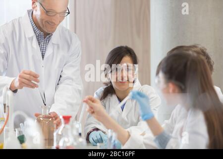 Male teacher and students conducting scientific experiment in laboratory classroom Stock Photo