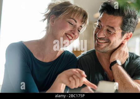 Happy couple using smartphone at home Stock Photo