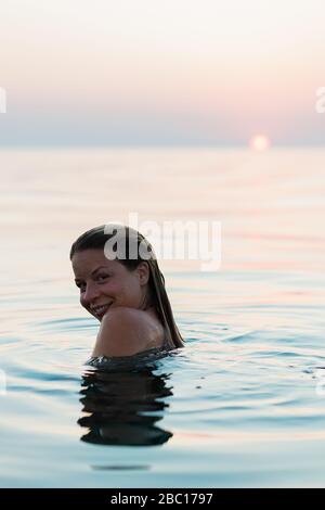 Young woman swimming in the sea in sunset