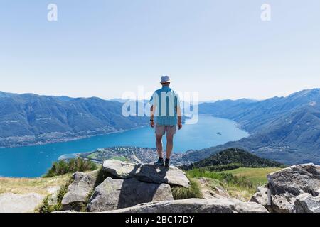 Hiker at Cimetta mountain top looking towards Lago Maggiore and Ascona, Locarno, Ticino, Switzerland Stock Photo