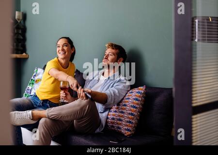 Young couple sitting on the couch at home watching tv Stock Photo
