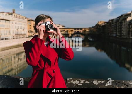 Young woman taking a picture on a bridge above river Arno, Florence, Italy Stock Photo