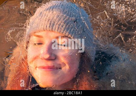Portrait of smiling teenage girl behind ice-covered surface Stock Photo