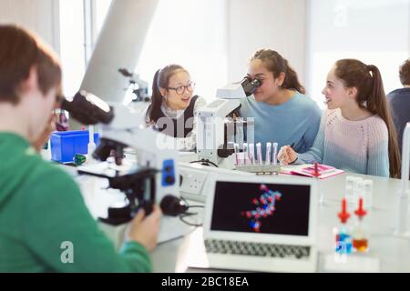 Girl students using microscope, conducting scientific experiment in laboratory classroom Stock Photo