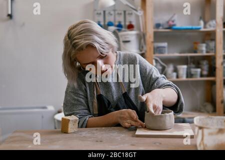 Young woman working on workpiece in pottery Stock Photo