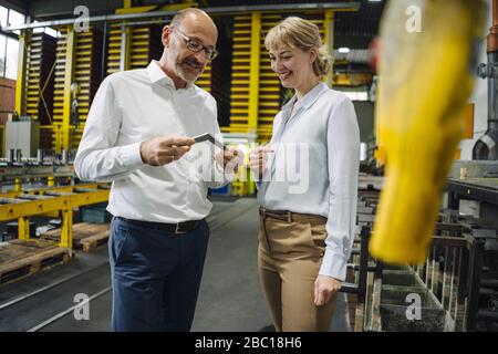 Man and woman examining workpiece in factory Stock Photo