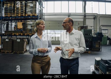 Man and woman walking and talking in a factory