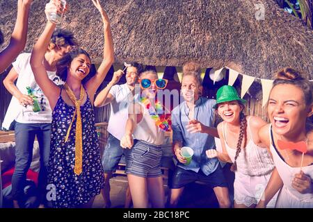 Portrait enthusiastic, playful young friends dancing and laughing at summer party Stock Photo