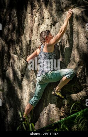 Female climber bouldering on rock, Avegno, Ticino, Switzerland Stock Photo