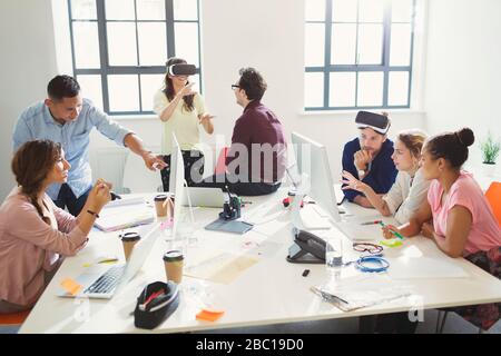 Computer programmers programming virtual reality simulator glasses in open plan office Stock Photo