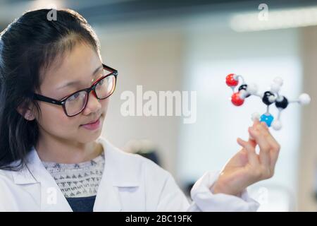 Curious girl student examining molecular structure in classroom Stock Photo