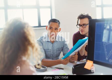 Designers discussing paperwork in office Stock Photo