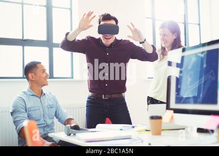 Computer programmers testing virtual reality simulator glasses in office Stock Photo