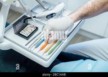 Close-up of dentist taking dental instrument from tray Stock Photo