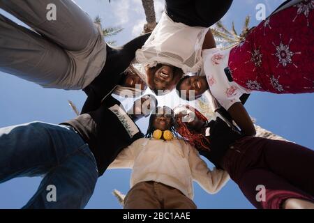 Portrait of happy teenage girlfriends and young man huddling under blue sky Stock Photo