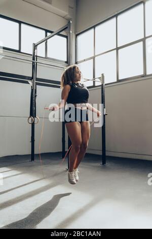 Young woman skipping rope in gym