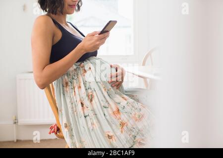 Pregnant woman in floral skirt holding stomach Stock Photo
