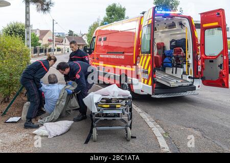 TAKING INTO CARE OF A MAN PASSED OUT ON THE PAVEMENT, FIREFIGHTERS FROM THE EMERGENCY SERVICES, AUXERRE, YONNE, FRANCE Stock Photo
