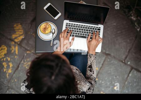 Top view of young woman using laptop at a pavement cafe Stock Photo